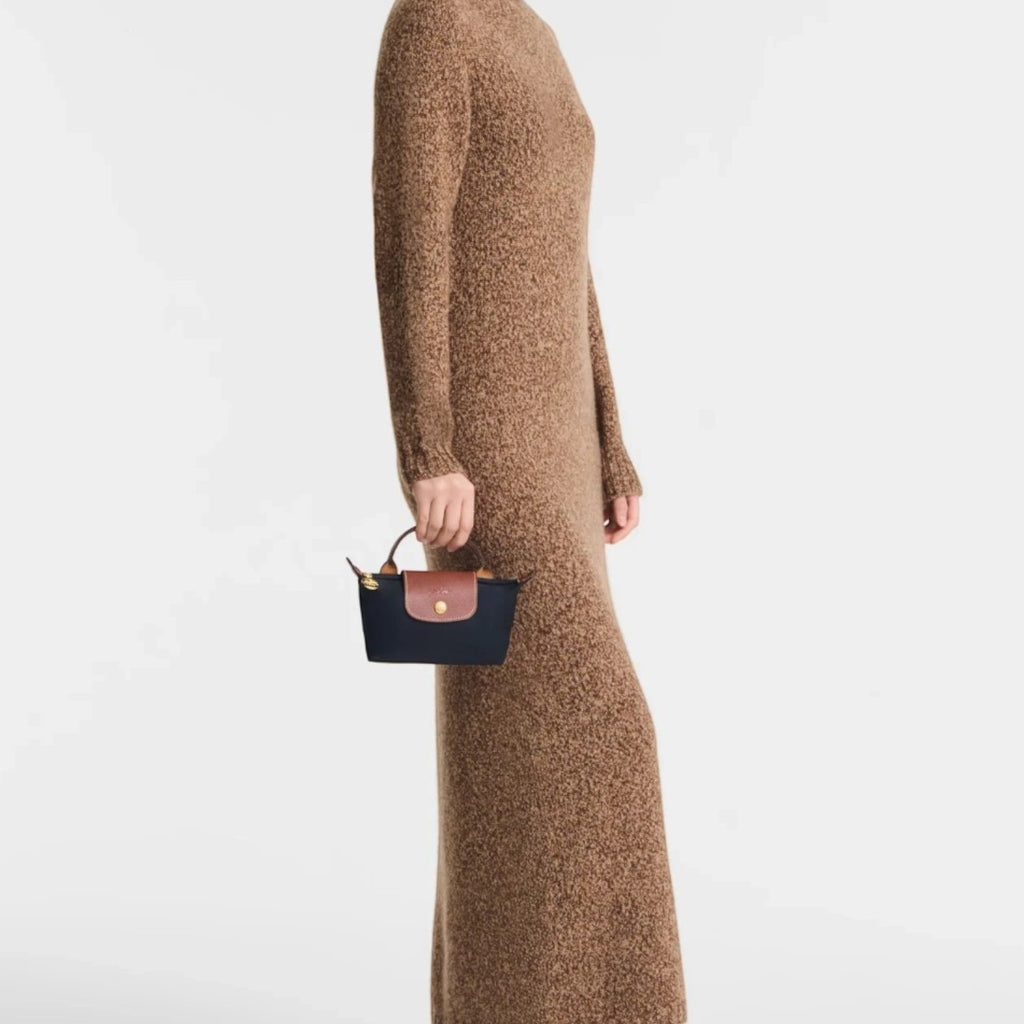 Lieblingstasche Longchamp Le Pliage Pochette in navy blue with brown leather trim held by a model in a brown dress