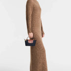Lieblingstasche Longchamp Le Pliage Pochette in navy blue with brown leather trim held by a model in a brown dress