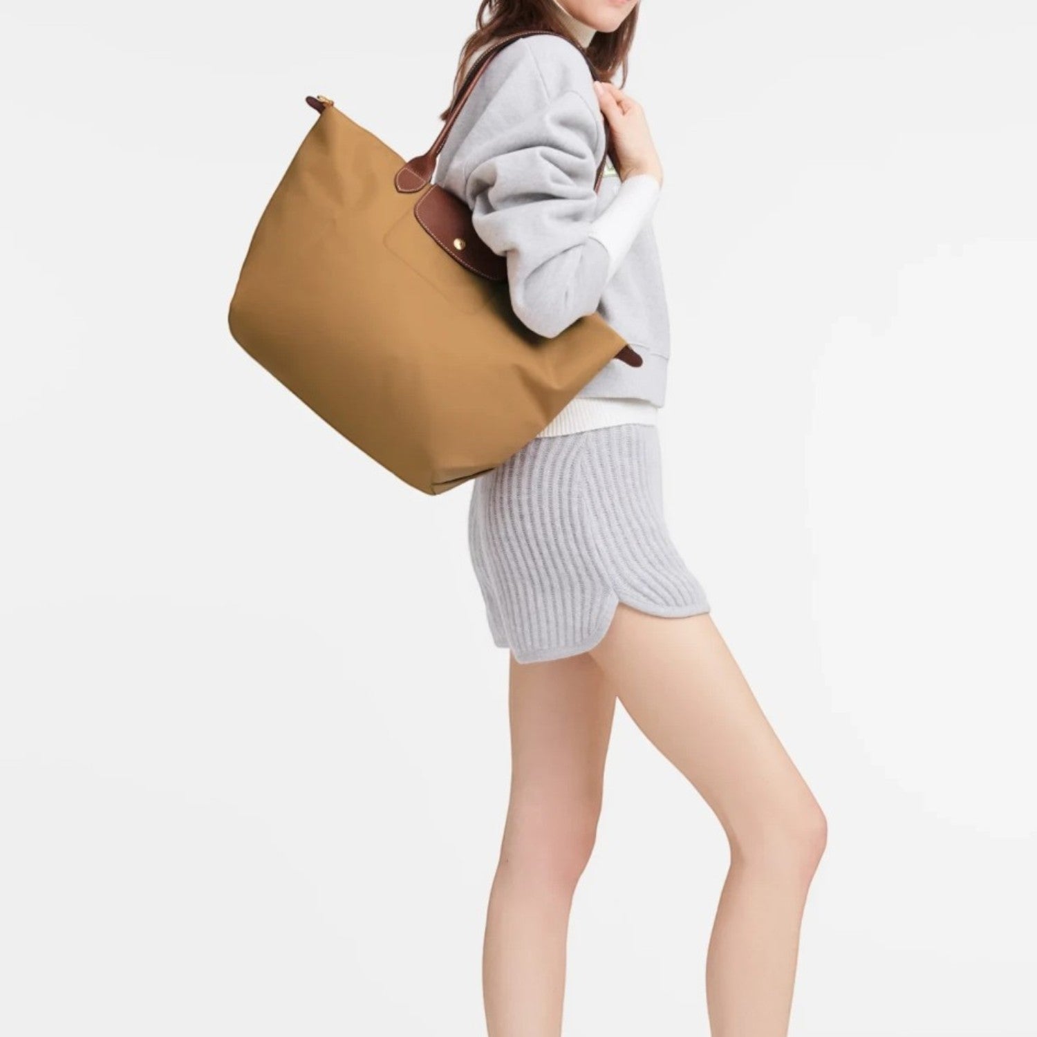 Model carrying a tan Longchamp Le Pliage shoulder bag from Lieblingstasche, featuring brown leather trim.