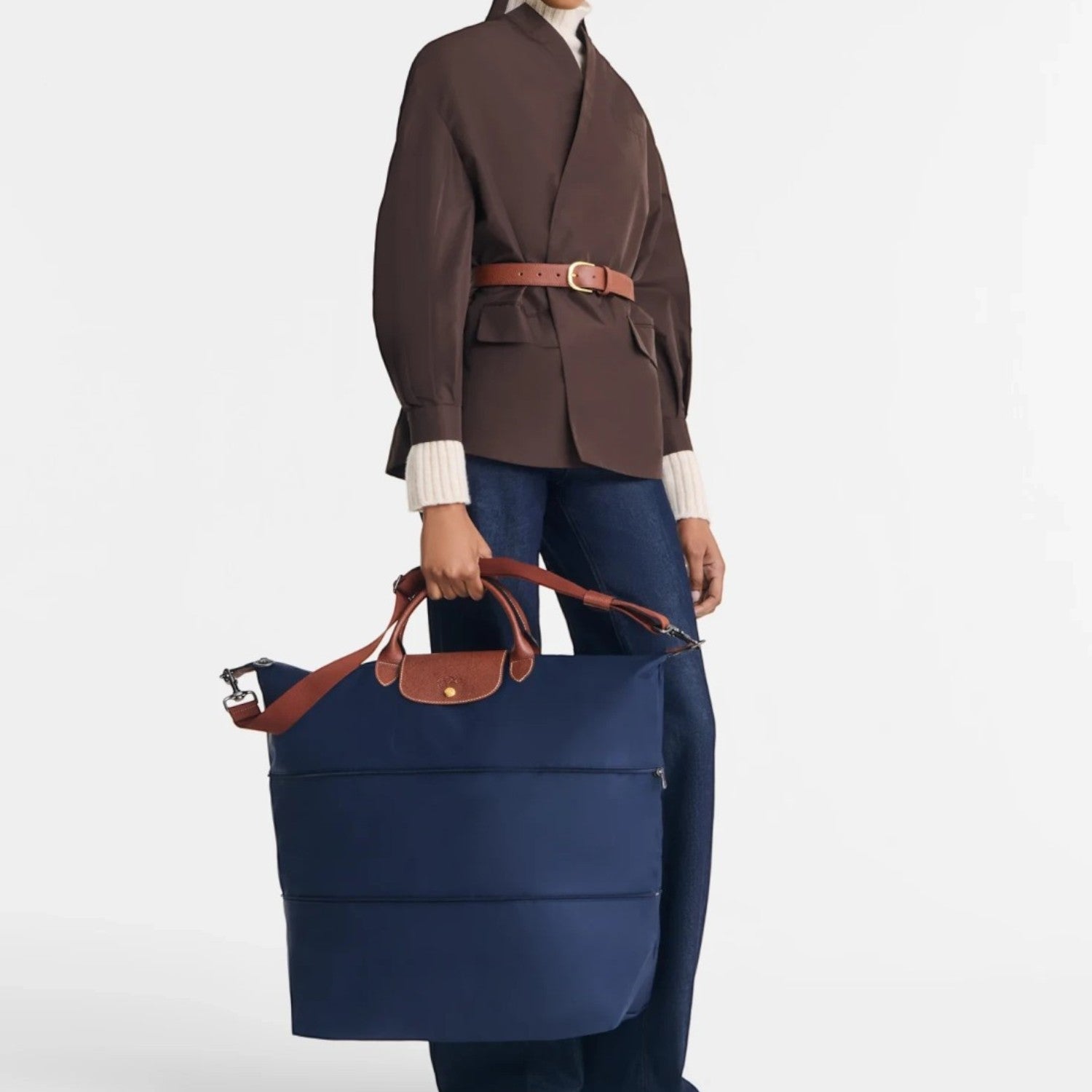 Model holding a navy blue Longchamp Le Pliage travel bag with brown leather handles from Lieblingstasche