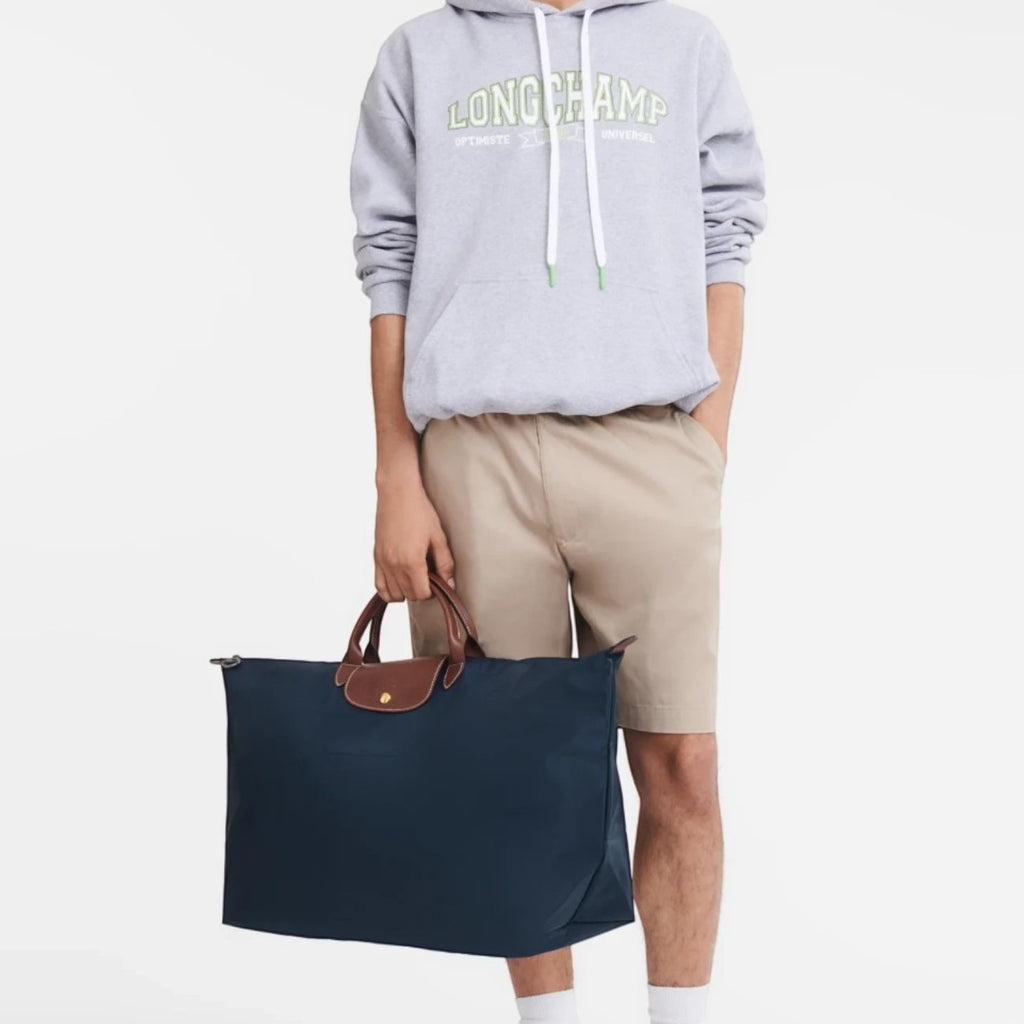 Lieblingstasche model holding a navy blue Longchamp Le Pliage XL travel bag with brown leather handles