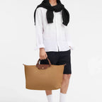 Lieblingstasche Longchamp Le Pliage travel bag in beige nylon with brown leather handles held by a male model