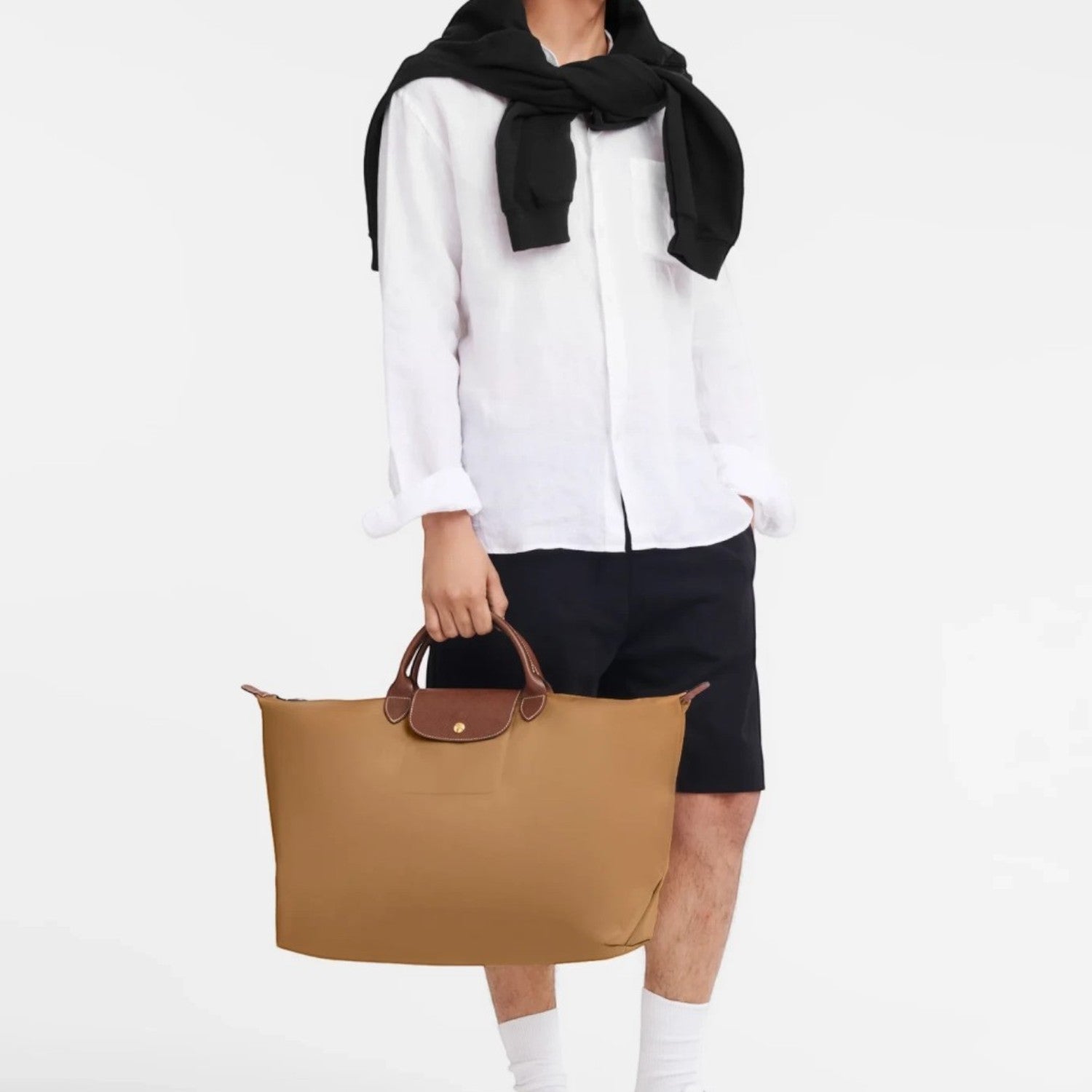 Lieblingstasche Longchamp Le Pliage travel bag in beige nylon with brown leather handles held by a male model
