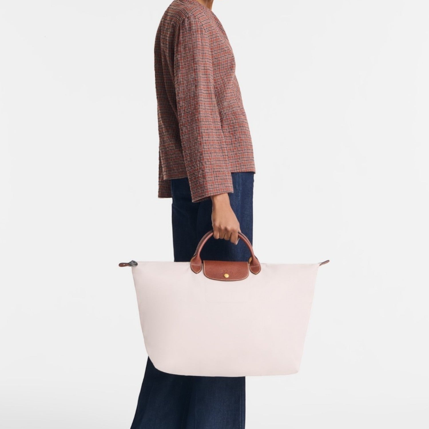 Model holding a large light pink Lieblingstasche Longchamp Le Pliage travel bag with brown leather handles