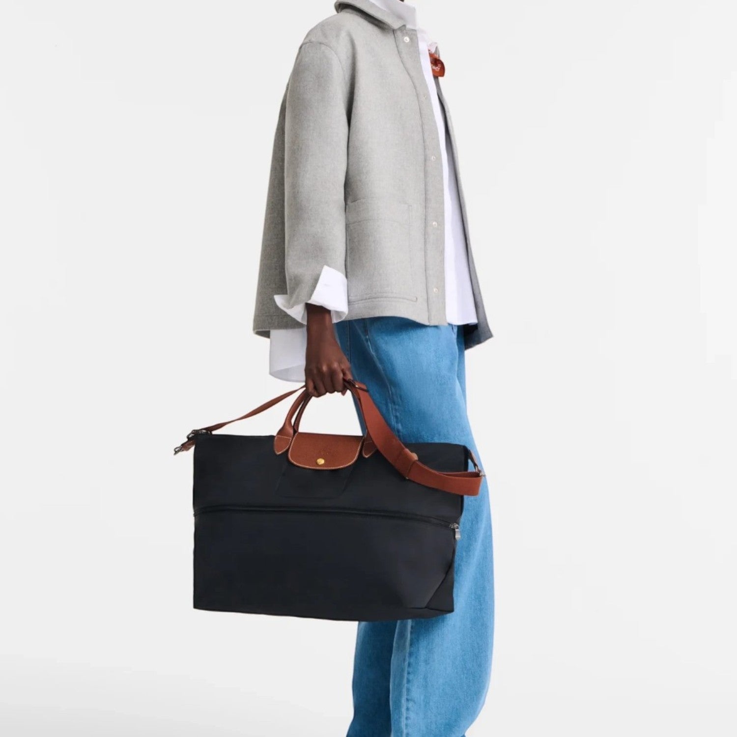 Model carrying a black Lieblingstasche Longchamp Le Pliage travel bag with brown leather handles and trim