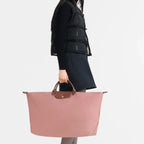 Lieblingstasche Longchamp Le Pliage XL travel bag in dusty pink with brown leather handles held by a model