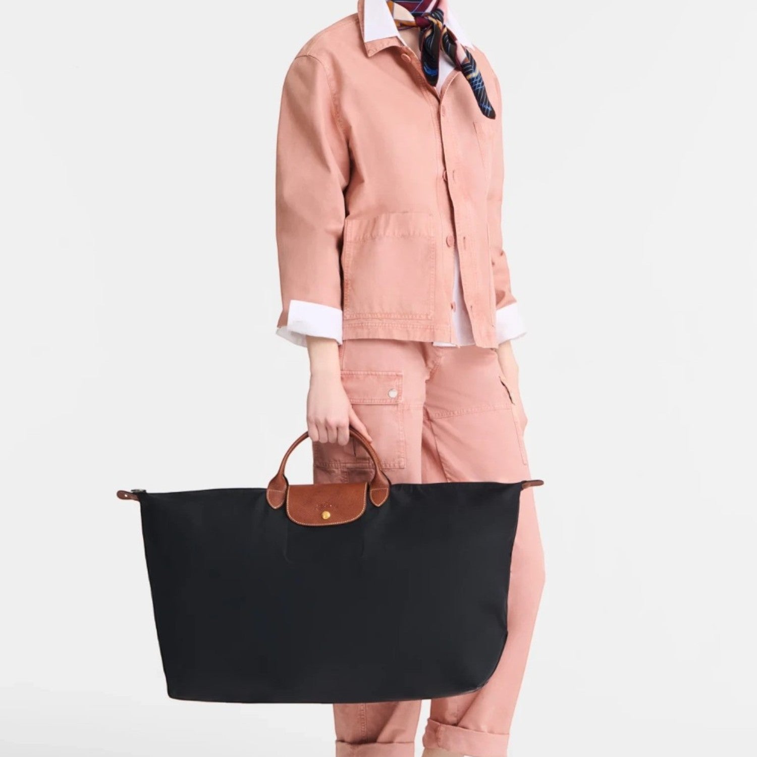 A model holding a black Longchamp Le Pliage XL travel bag from Lieblingstasche, featuring brown leather handles.