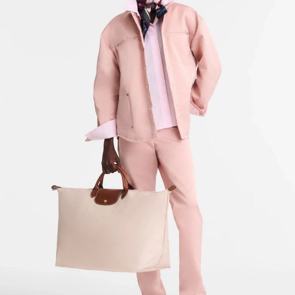 Model holding a beige Longchamp Le Pliage XL travel bag with brown leather handles from Lieblingstasche