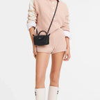 Lieblingstasche Longchamp Le Pliage Xtra black crossbody pochette worn by a model in a pink knit outfit