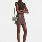 Model wearing a light green Longchamp Le Pliage Xtra crossbody pochette from Lieblingstasche with a brown outfit.