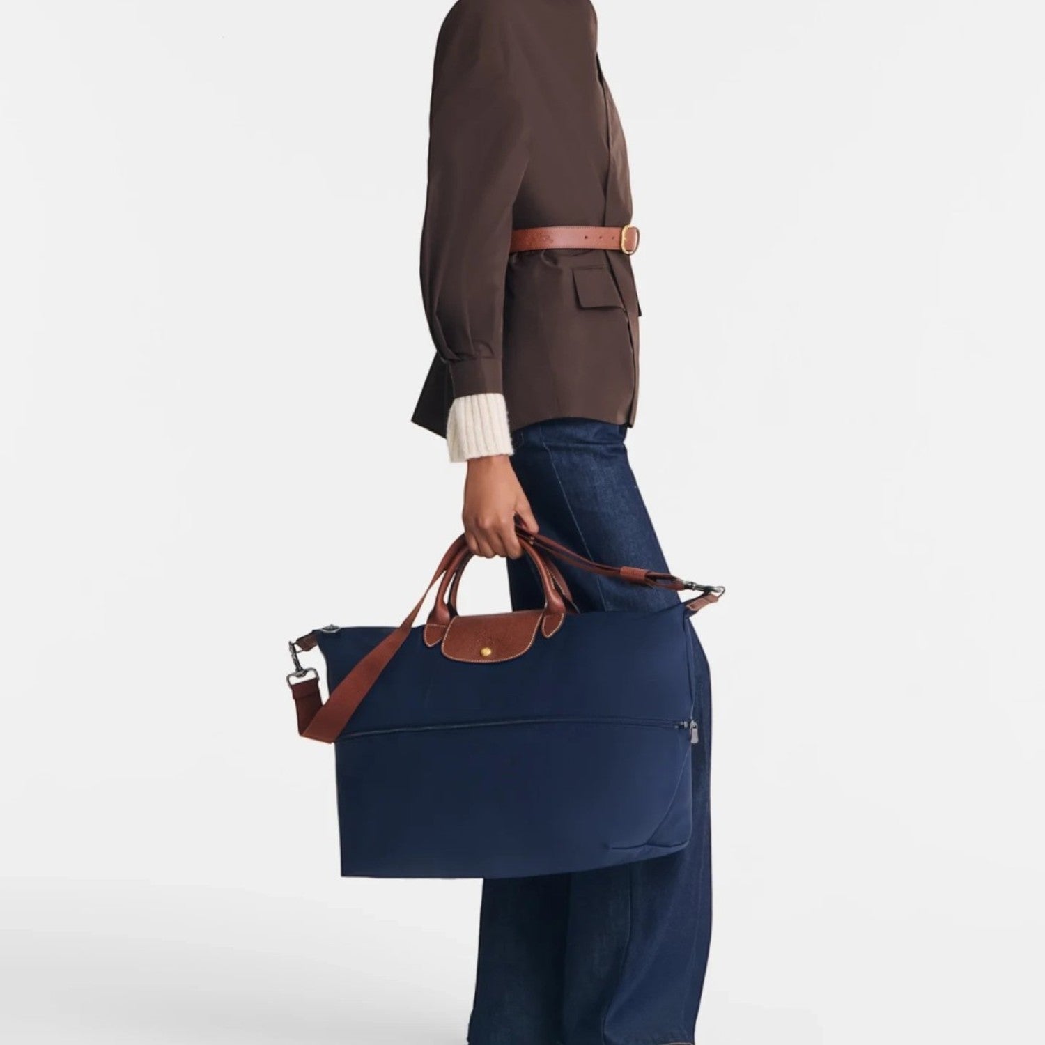 Model carrying a navy blue Longchamp Le Pliage travel bag with brown leather handles by Lieblingstasche