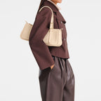 Lieblingstasche Looong shoulder bag in beige worn by a model in a brown jacket and leather trousers