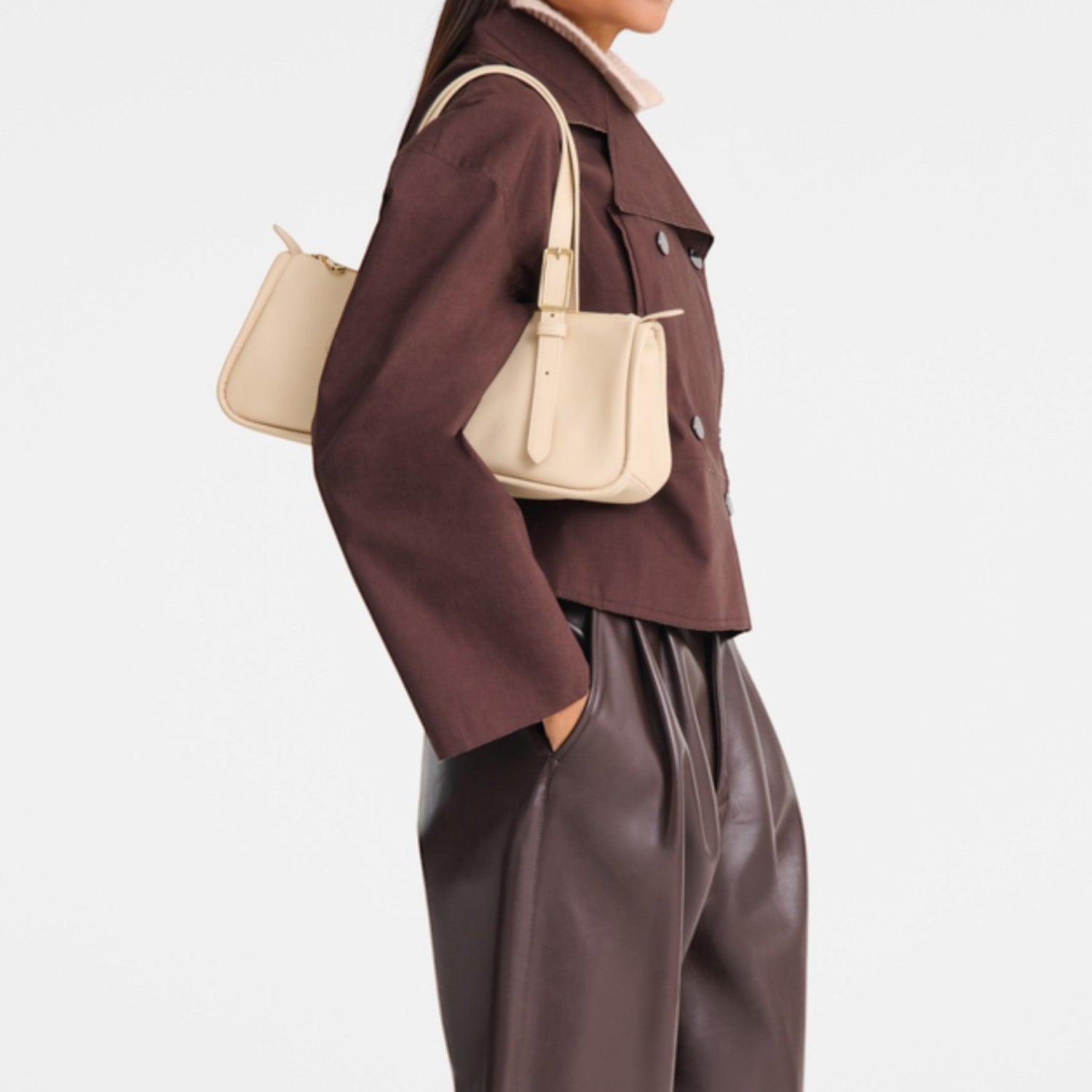 Lieblingstasche Looong shoulder bag in beige worn by a model in a brown jacket and leather trousers
