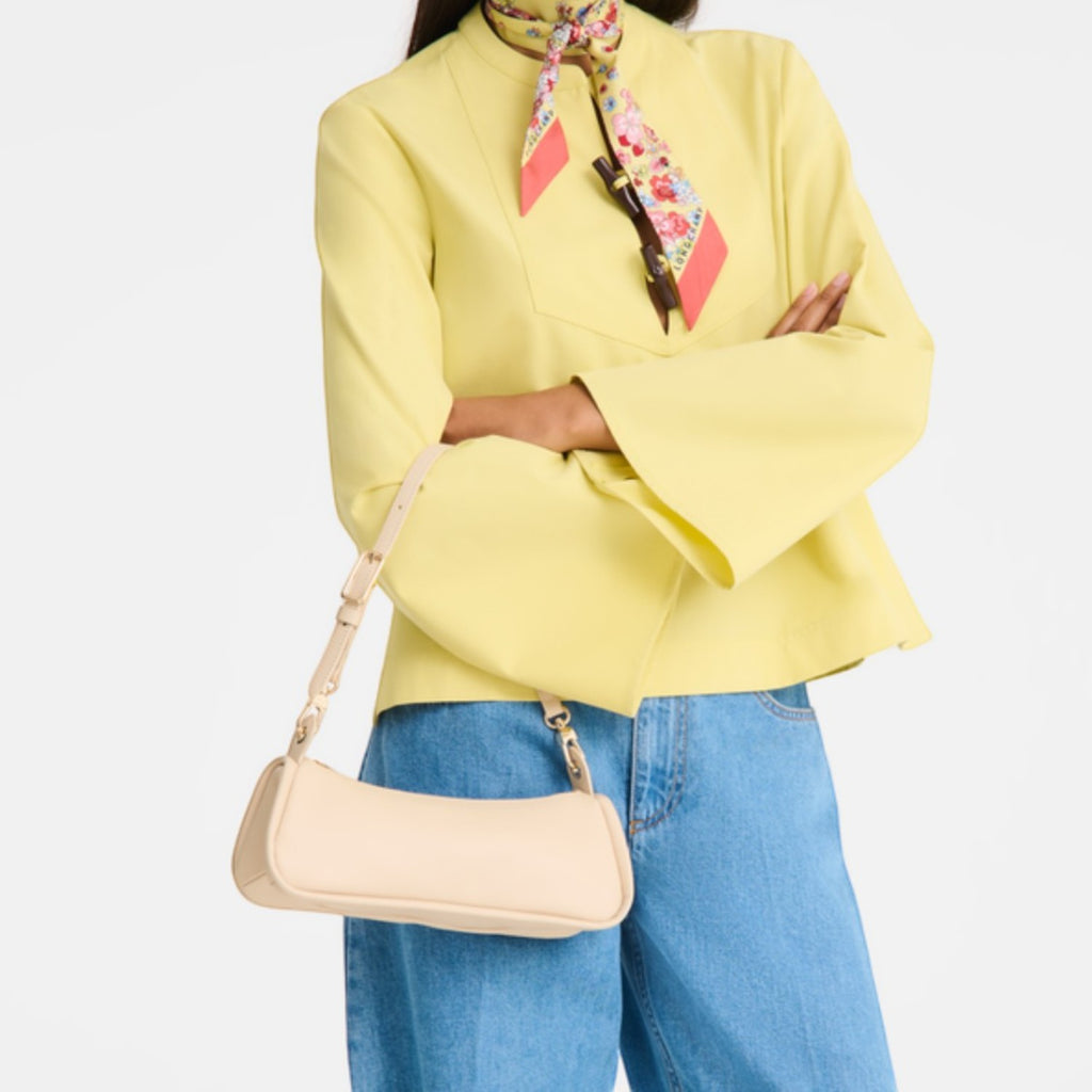 Lieblingstasche Looong Schultertasche S in beige worn by a model in a yellow blazer and blue jeans