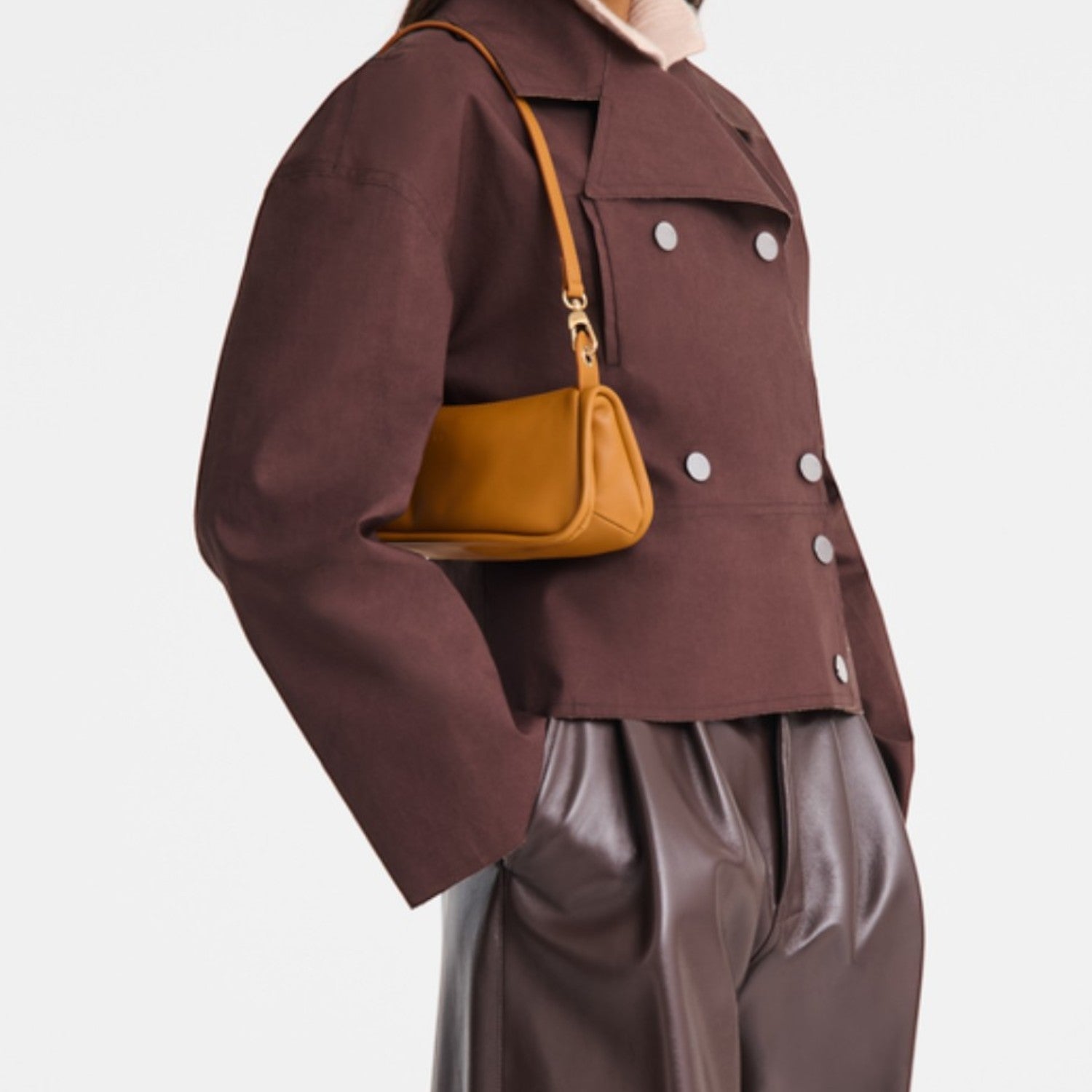Model wearing a Lieblingstasche Looong Schultertasche S in mustard yellow, styled with a brown jacket and trousers.