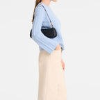 Lieblingstasche Looong Schultertasche S in black worn over the shoulder by a woman in a light blue sweater