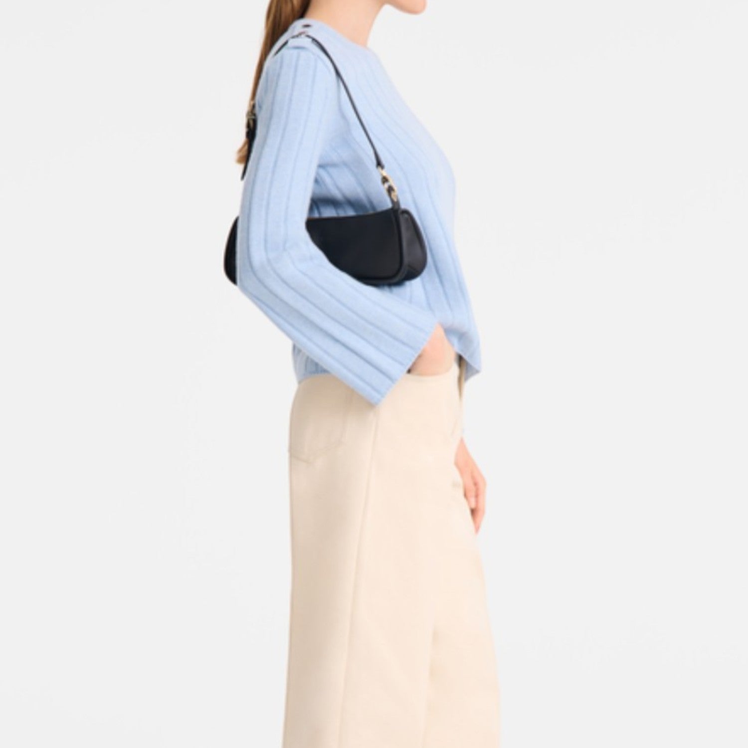 Lieblingstasche Looong Schultertasche S in black worn over the shoulder by a woman in a light blue sweater