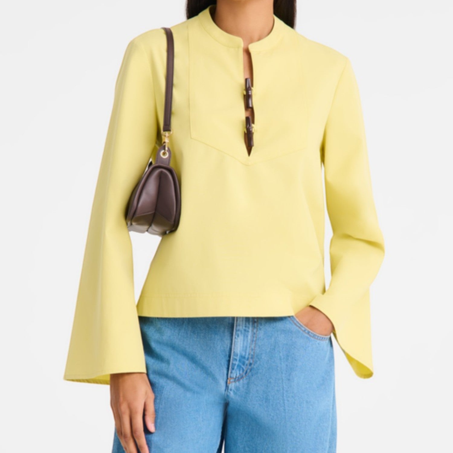 Lieblingstasche Looong Schultertasche S in dark brown worn as a shoulder bag by a model in a yellow top