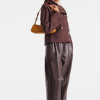 Model wearing a brown jacket and leather trousers carrying a tan Lieblingstasche Looong Schultertasche S bag