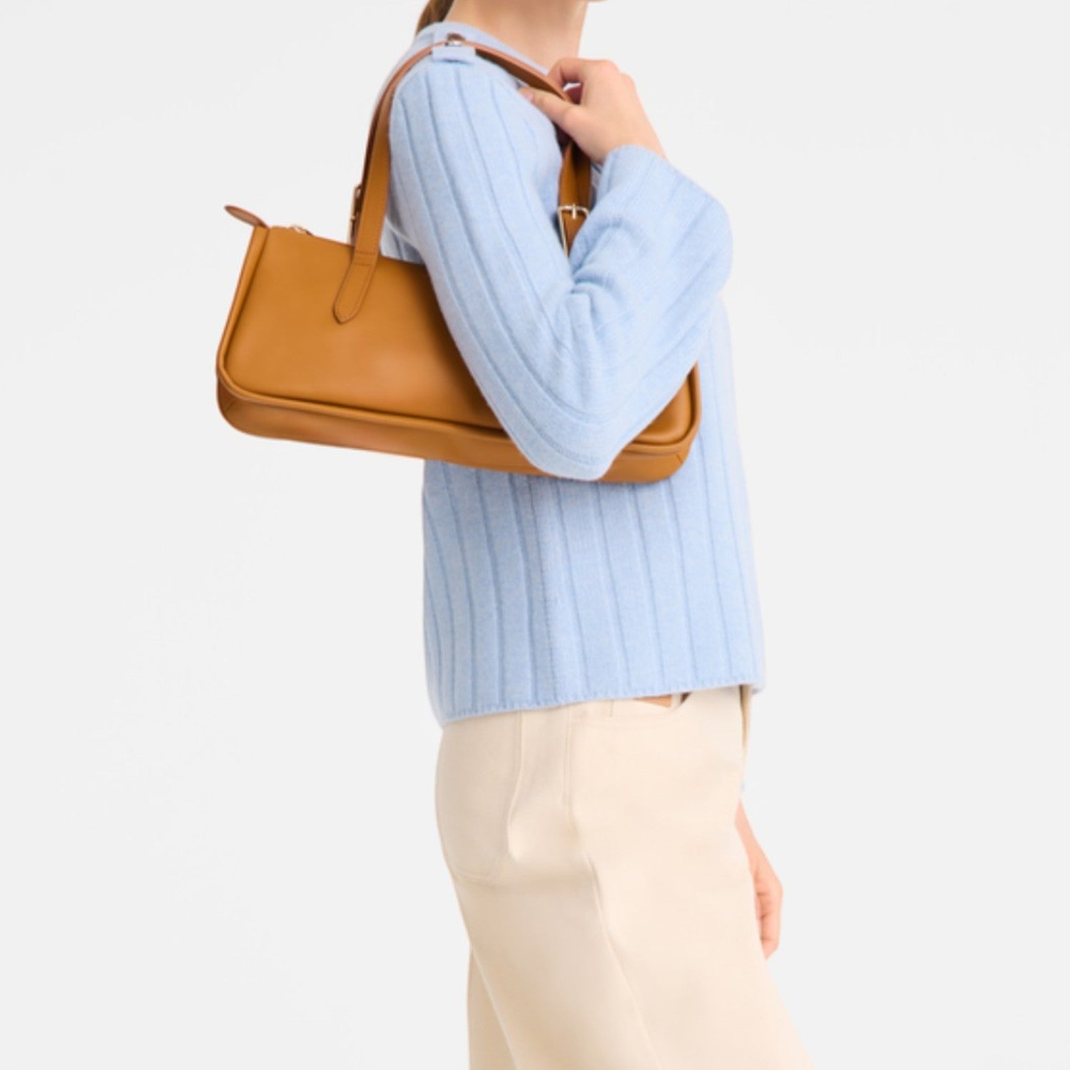 Lieblingstasche Looong shoulder bag in tan leather with a slim rectangular silhouette carried by a woman