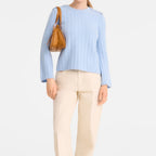 Lieblingstasche Looong shoulder bag in tan leather worn by a model in a light blue sweater and cream trousers