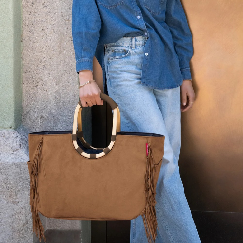 Lieblingstasche Loopshopper L brown suede tote bag with fringe details and rounded wooden handles held by a woman