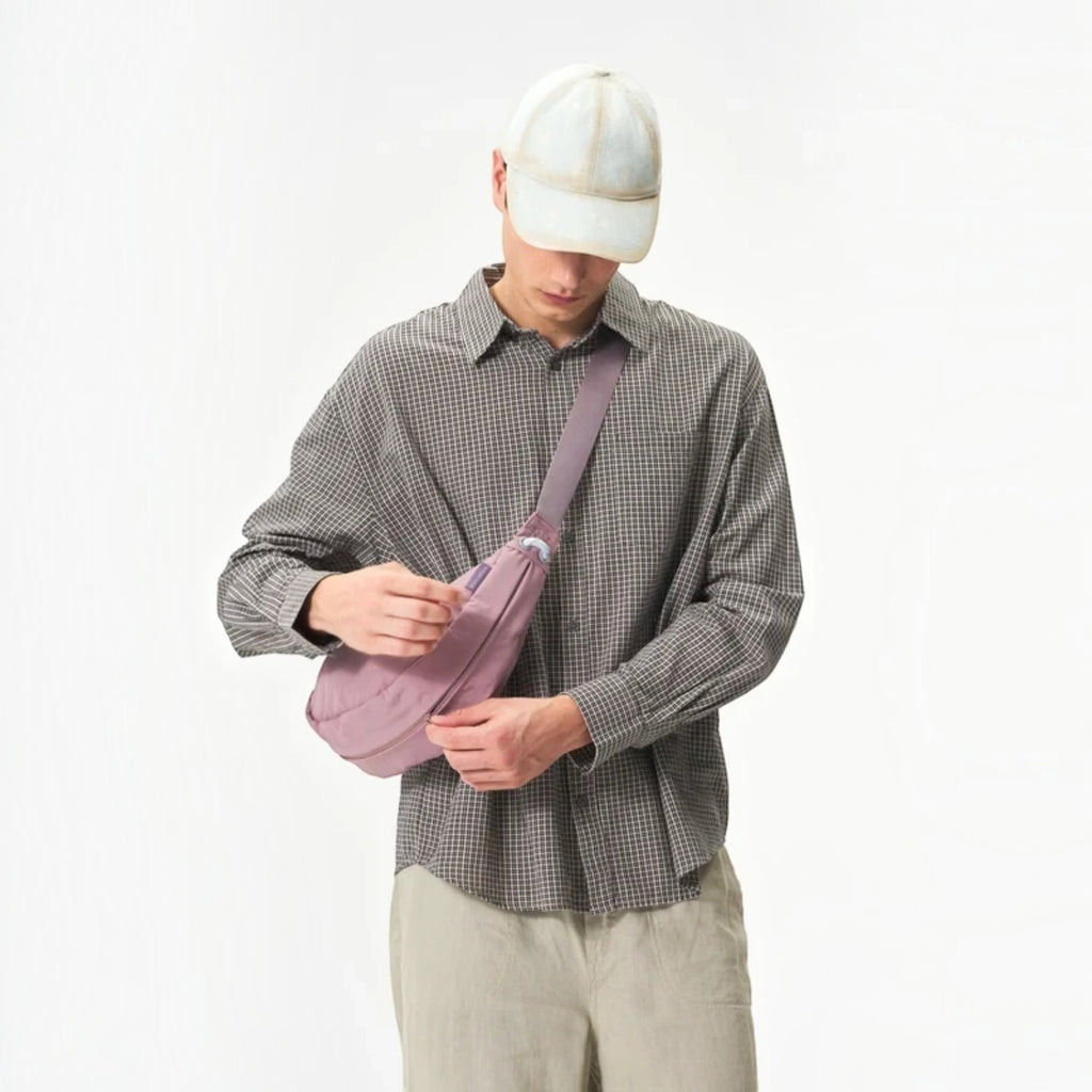 Lieblingstasche mauve water-resistant sling bag worn crossbody by a man in a checkered shirt and baseball cap