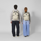 Two people wearing Lieblingstasche Midi20 beige minimalist 20L city backpacks with padded straps on a grey background
