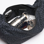 Lieblingstasche Moon Bag Ruffle Large in black leopard print with an open interior containing a water bottle and keys.