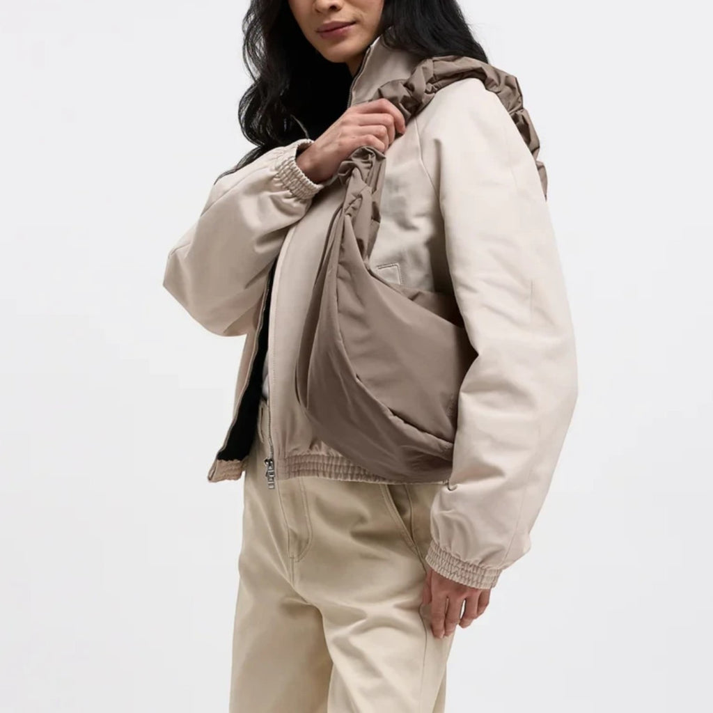 Lieblingstasche Moon Bag Ruffle Large in taupe, worn as a crossbody bag by a model in a beige jacket.
