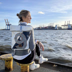 Lieblingstasche Möwe backpack with roll-top closure and number 9 design, worn by a woman at the harbor.