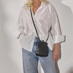 Lieblingstasche Mrs. Sugar Pop vintage style black leather crossbody bag with clip closure worn by a smiling woman