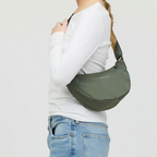 Lieblingstasche Essential Moon Bag in olive green worn over the shoulder by a woman in a white long-sleeve top