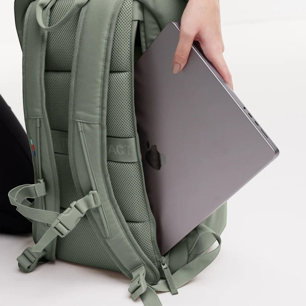 Lieblingstasche Pro Pack sage green backpack with a laptop being inserted into the external 15-inch compartment.