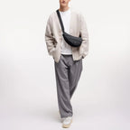 Lieblingstasche Puffer Moon Bag Small in black, worn crossbody by a model in a beige cardigan and grey trousers.