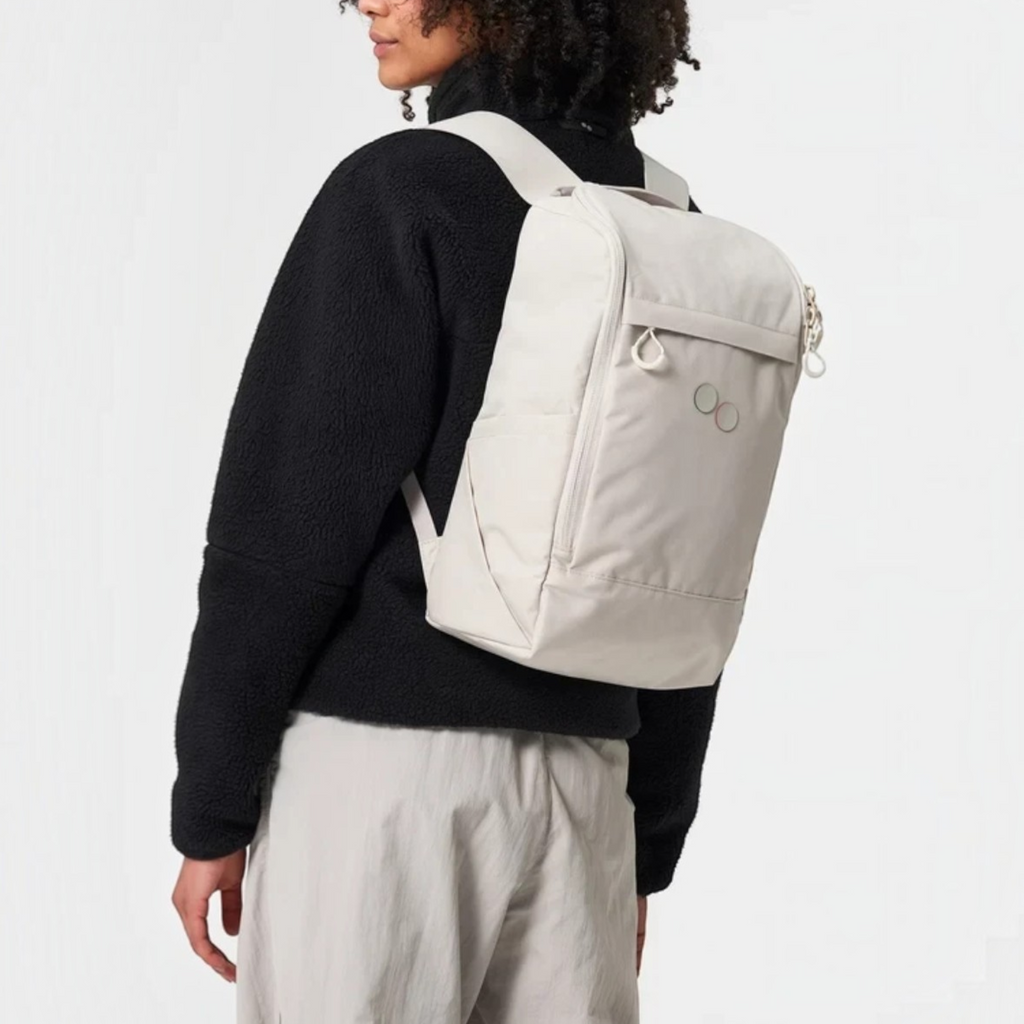 Lieblingstasche Purik backpack in light beige worn by a woman with curly hair against a plain studio background