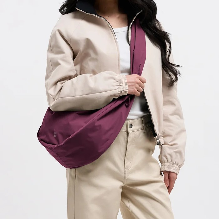 Lieblingstasche Moon Bag Ruffle Large in deep purple worn as a crossbody bag by a woman in a beige jacket