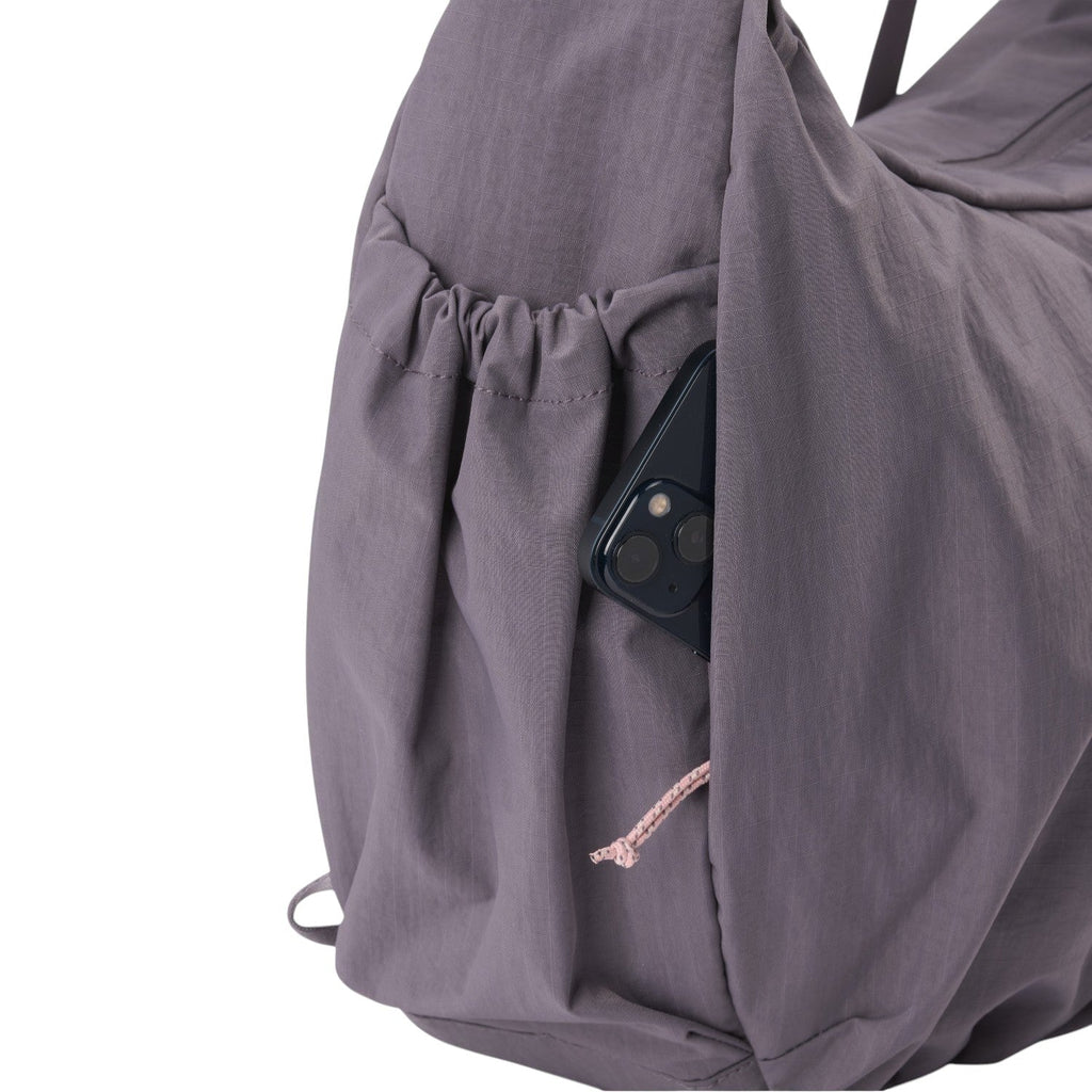 Lieblingstasche slouchy bag in dusty purple nylon with a convenient side pocket holding a smartphone