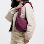 Lieblingstasche Moon Bag Ruffle Large in deep purple with a gathered shoulder strap worn over a beige jacket