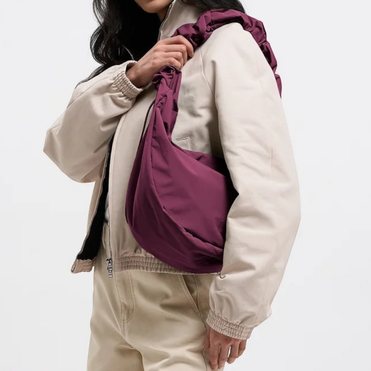 Lieblingstasche Moon Bag Ruffle Large in deep purple with a gathered shoulder strap worn over a beige jacket