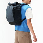Lieblingstasche Roll Pack 2.0 grey and black rolltop backpack worn by a man in a blue sweater vest