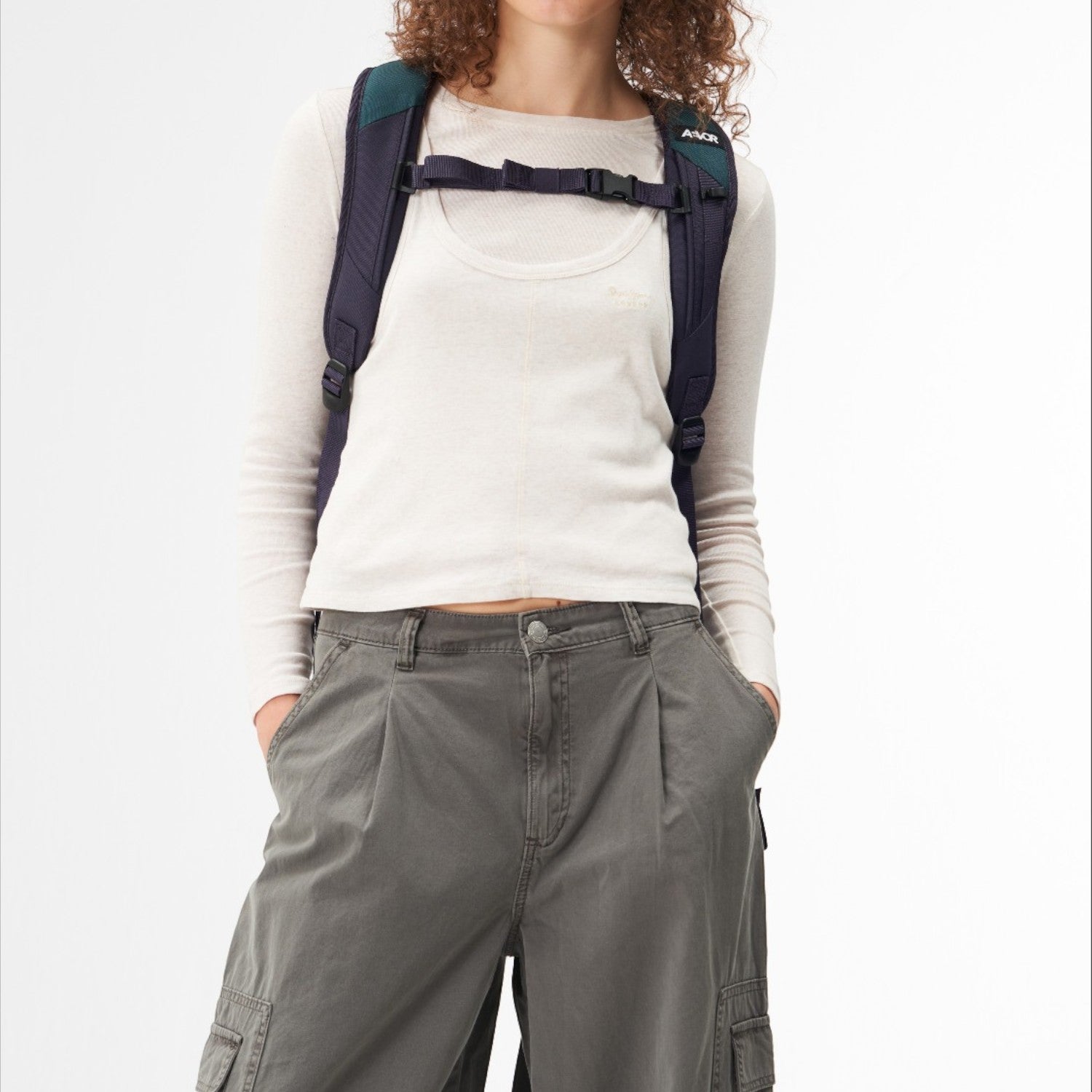 Model wearing a dark blue Lieblingstasche Roll Pack 2.0 backpack with adjustable chest strap on a white background