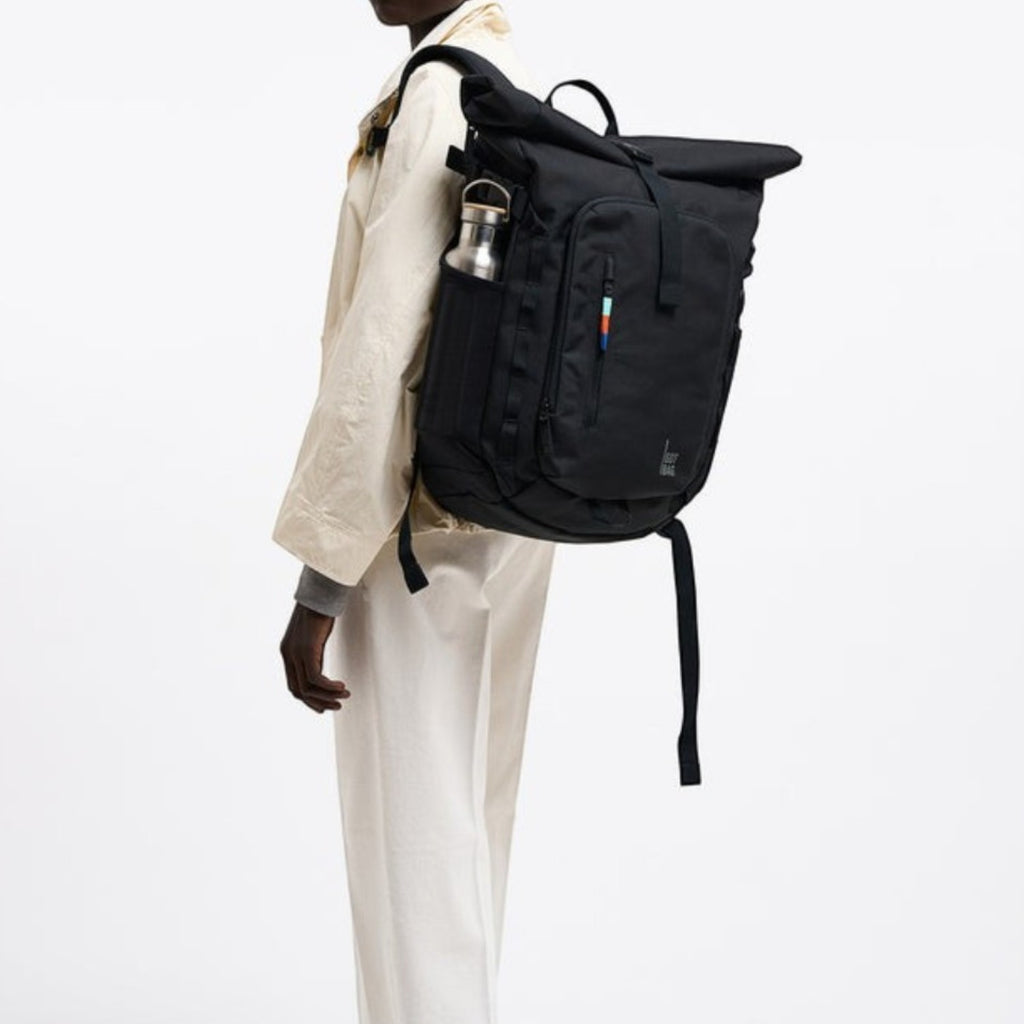 Lieblingstasche Rolltop Adventure black backpack with water bottle pocket and rainbow detail on a model.
