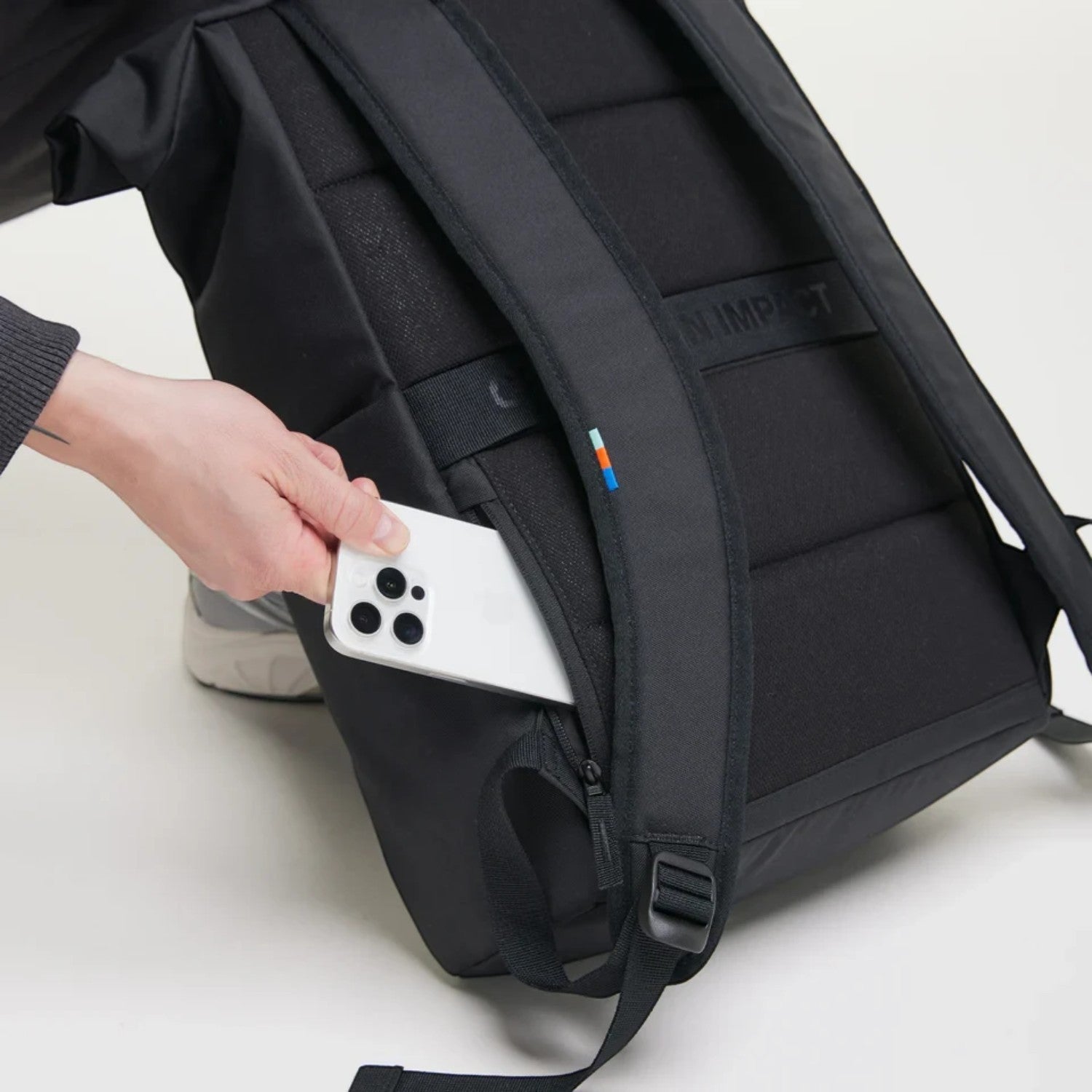 Lieblingstasche Rolltop Easy black backpack with a hand placing a smartphone into the side zipper pocket