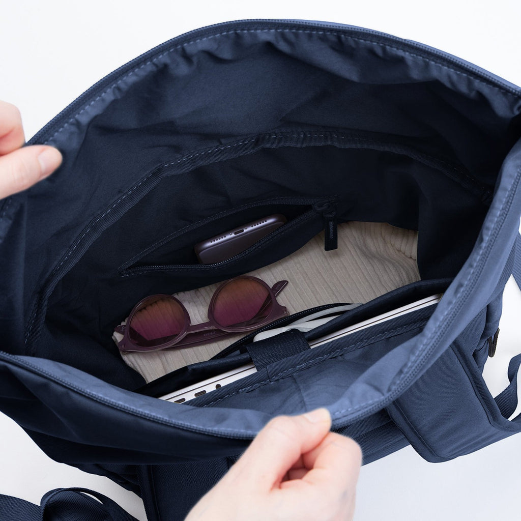 Lieblingstasche Rolltop Easy navy blue backpack interior with laptop, sunglasses, and phone