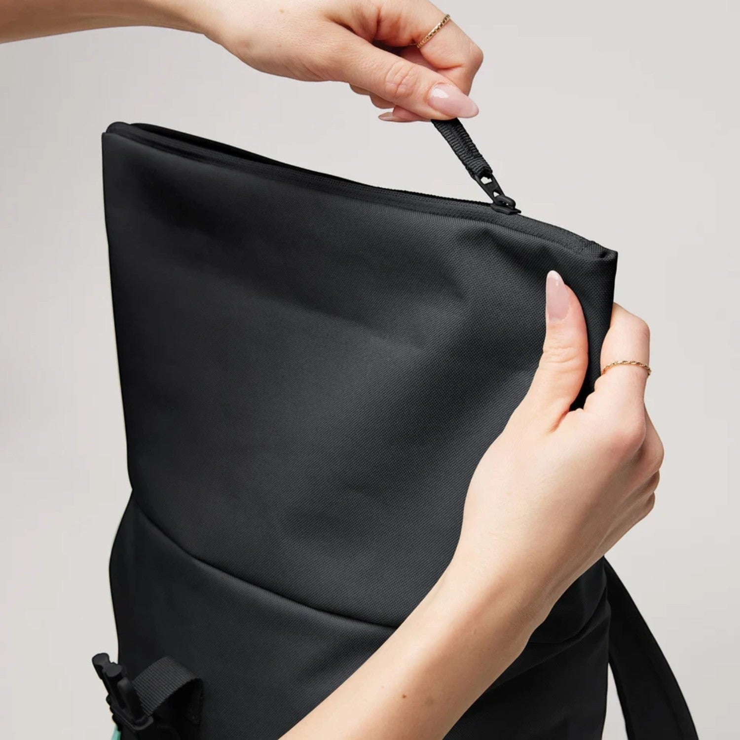 Lieblingstasche Rolltop Easy Small backpack in black with hands opening the zipper closure