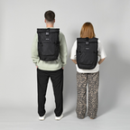 Lieblingstasche Rolly32 black recycled rolltop backpack worn by a man and a woman, back view