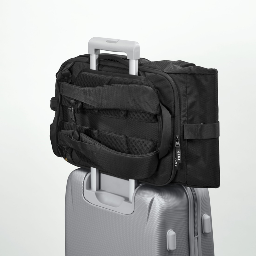 Lieblingstasche Rolly32 black rolltop backpack attached to a silver suitcase trolley handle for travel