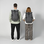Lieblingstasche Rolly32 grey rolltop backpack worn by a man and woman, showing the back view and adjustable straps.