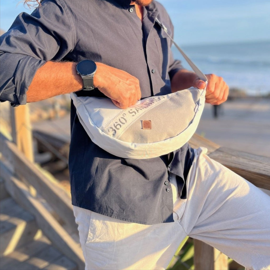 Lieblingstasche Roop moonbag made from recycled white sailcloth with maritime stitching worn by a man at the beach